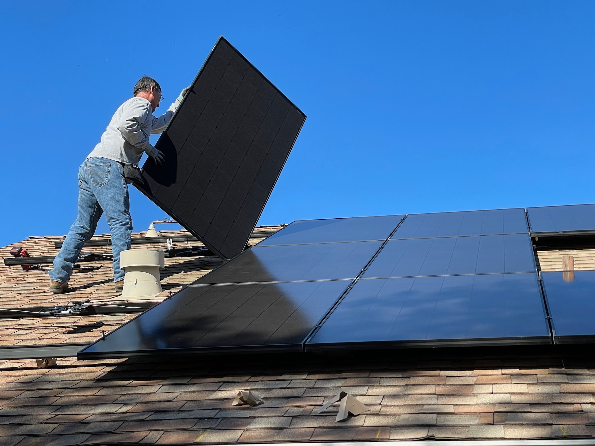 man installing solar panels on a roof